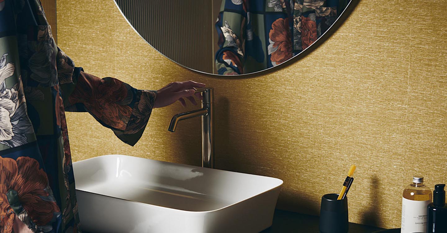 Photo de la collection Ipalyss mise en ambiance montrant une personne devant une vasque avec un miroir rond au-dessus