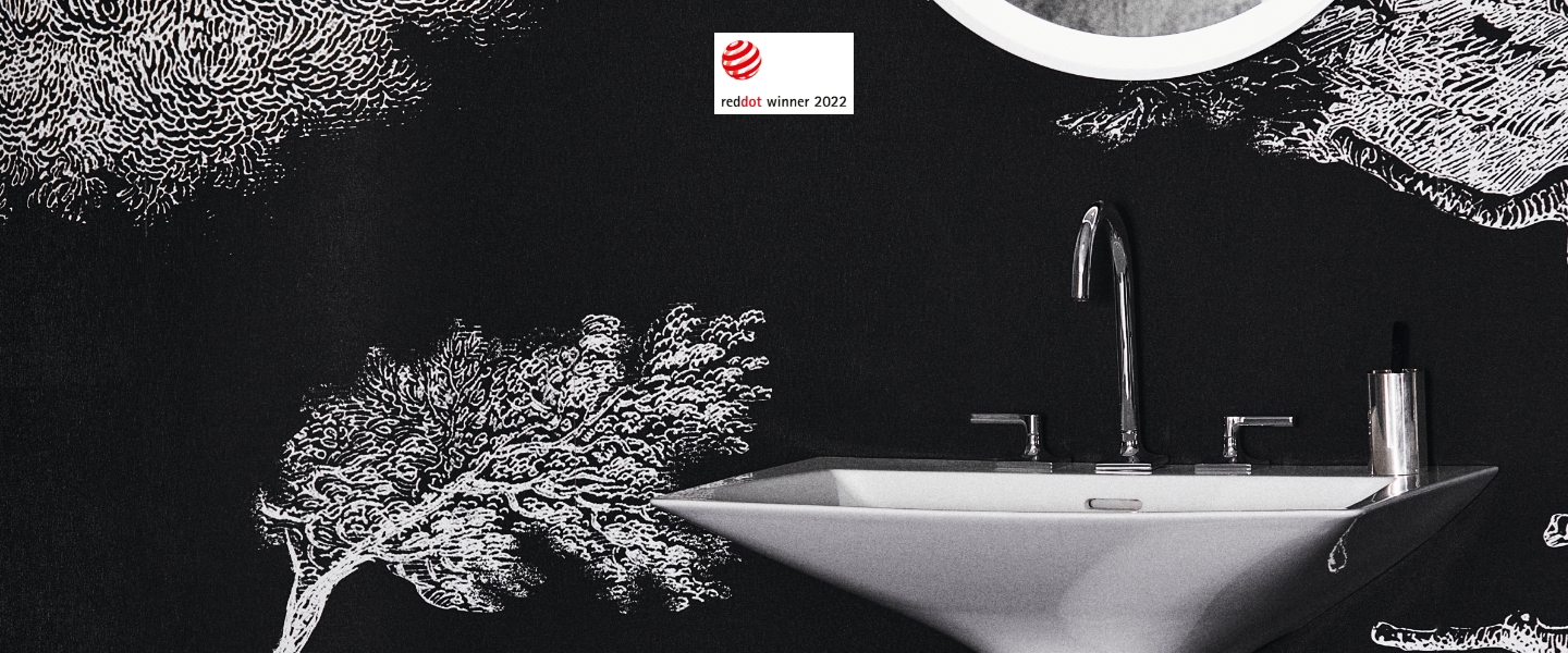 Photo du mélangeur chrome Joy Neo d'Ideal Standard installé sur le lavabo monobloc blanc Tipo-Z. En arrière-plan, tapisserie noir avec motifs blancs d'arbres et feuillages.